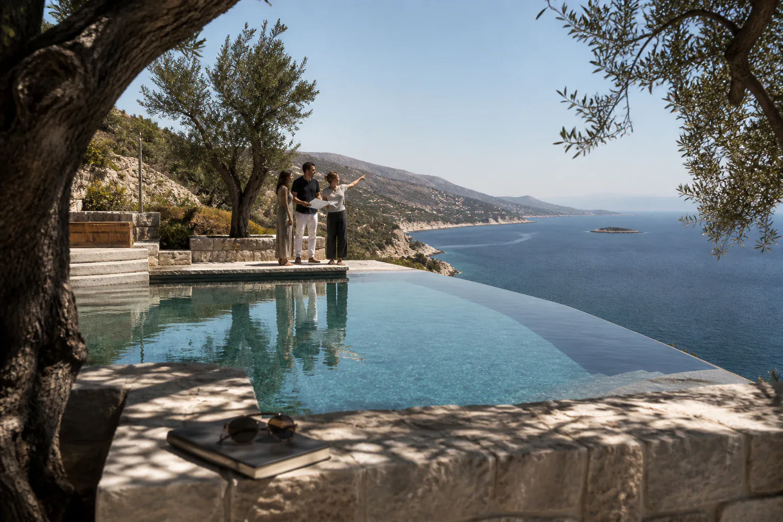 Editorial concept of a villa specialist reviewing a coastal shortlist with two travellers
