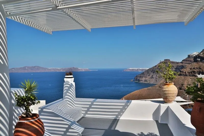 Striped pergola shade over a whitewashed terrace above the caldera