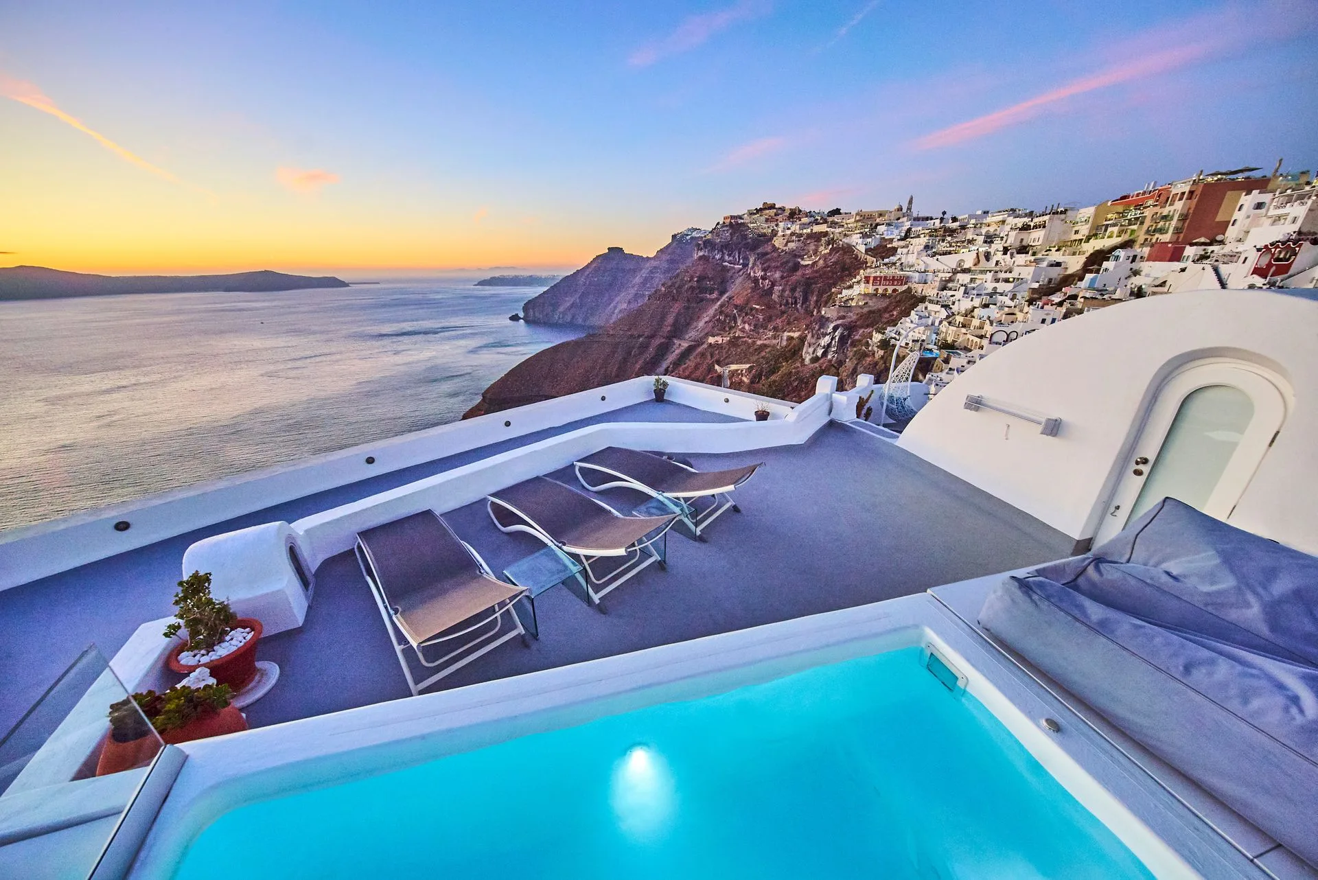 A heated tub glowing at dusk on a terrace above the Santorini caldera