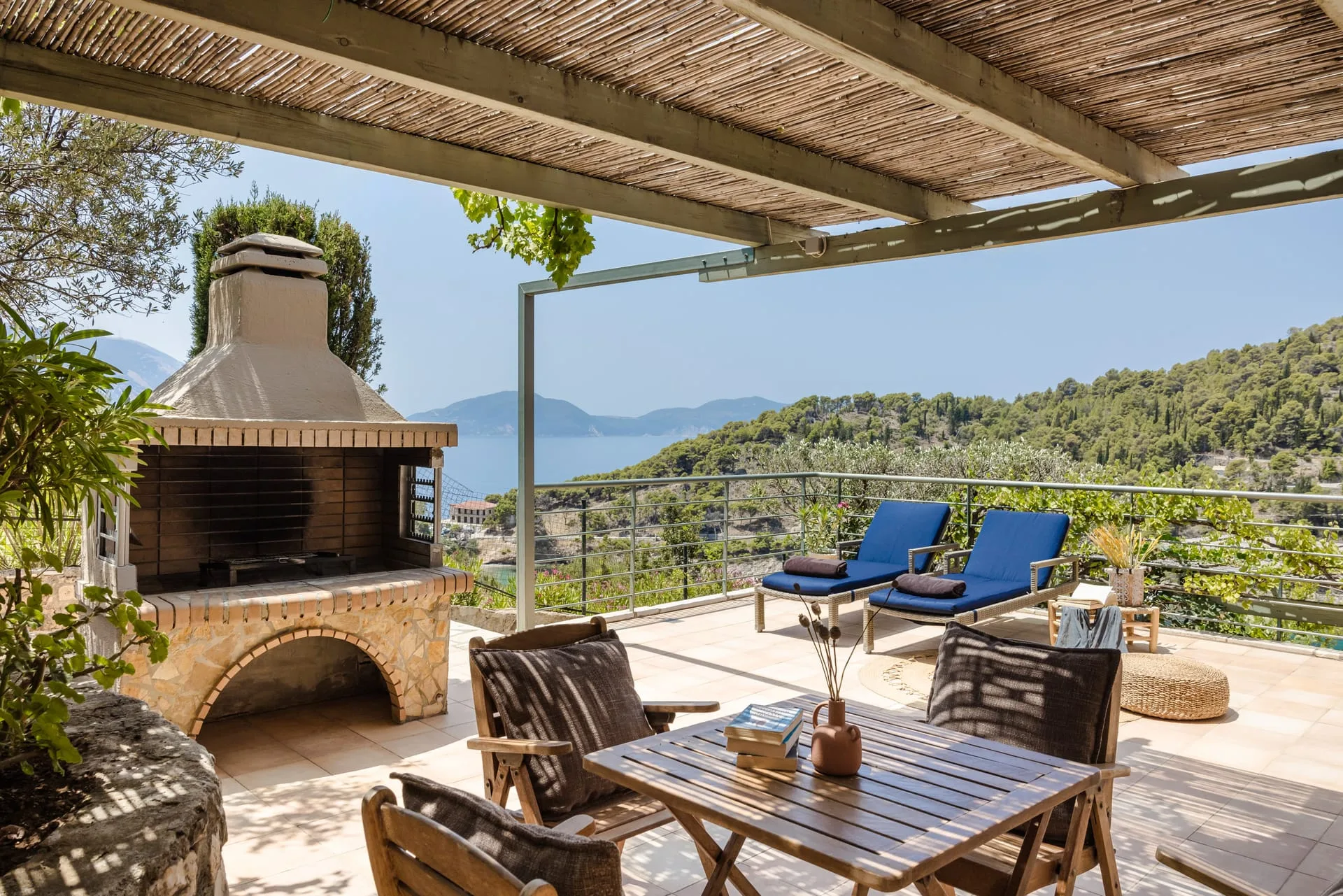 Covered outdoor dining terrace with barbecue overlooking the bay at Braunis Horio
