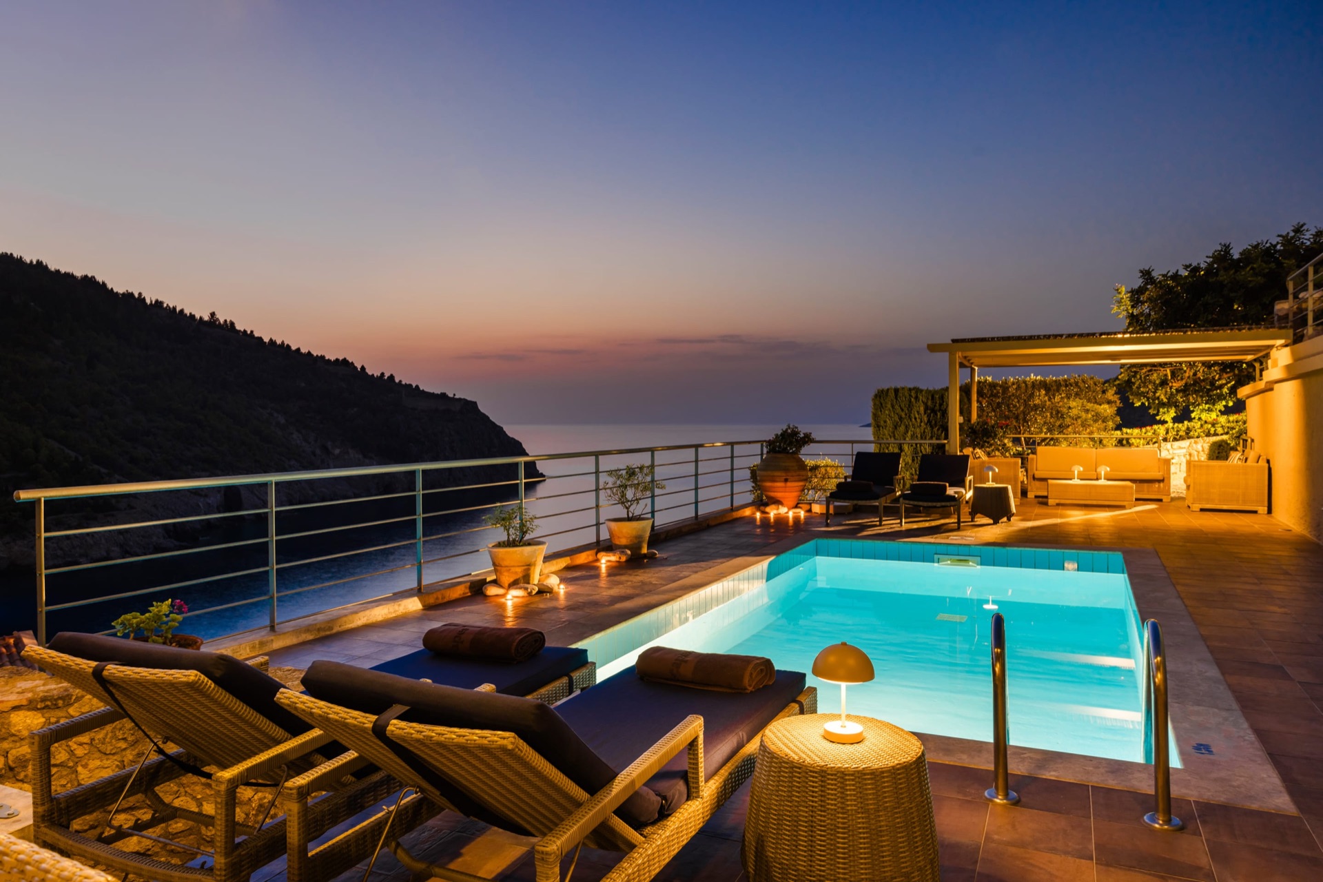 Villa Thea pool terrace lit at dusk above the bay of Assos