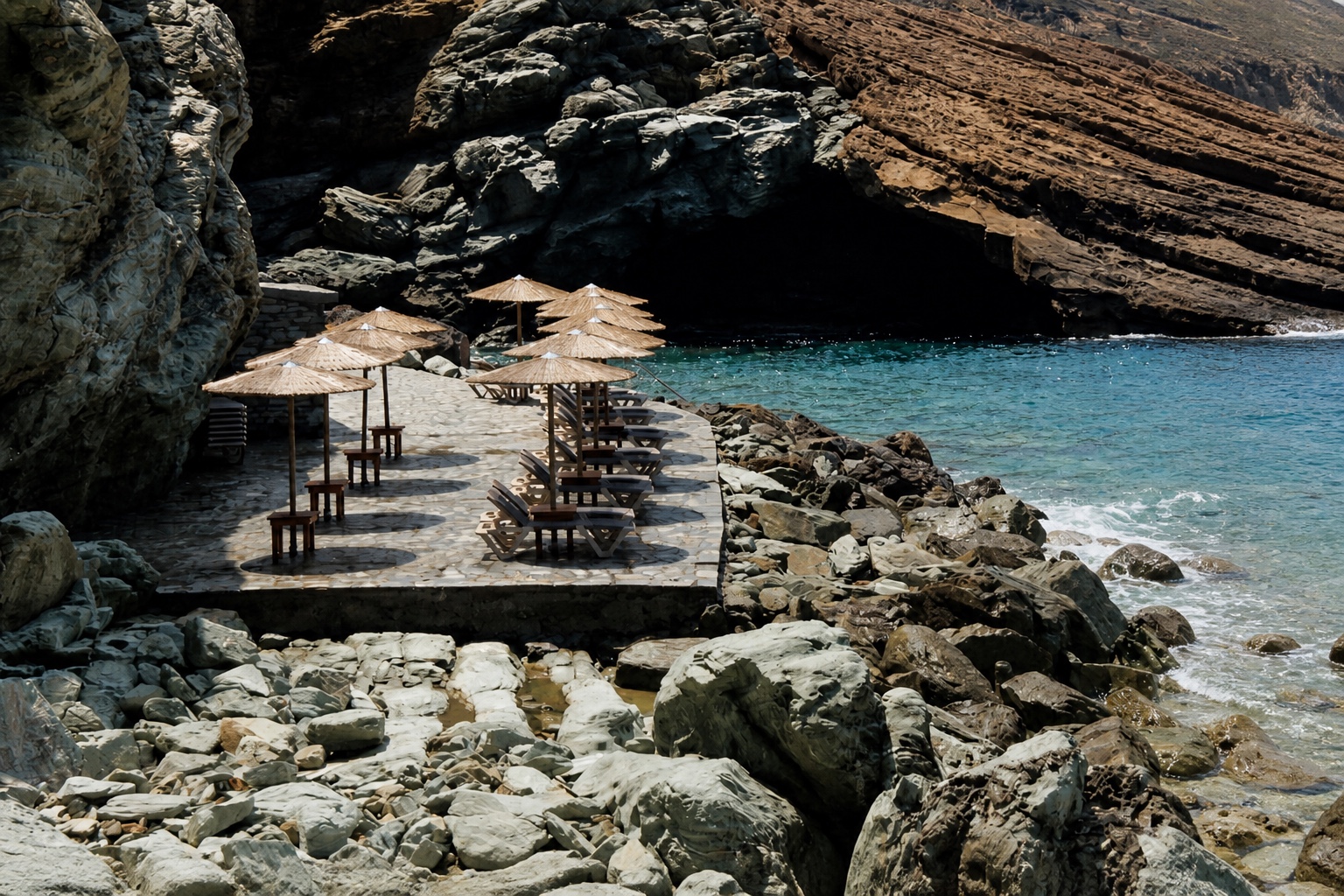 Natural-stone sea platform with sunbeds and parasols in Rock Bay