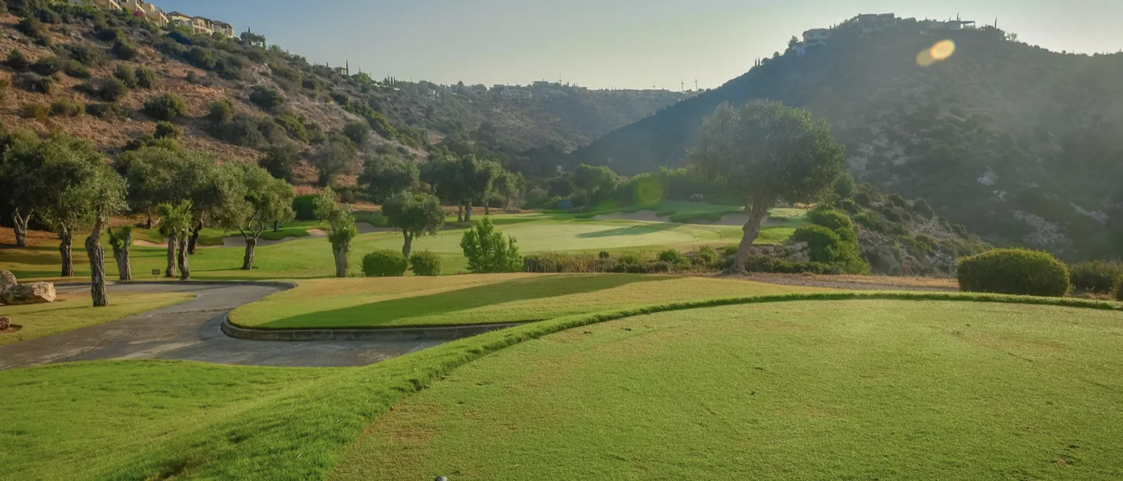 Manicured fairway and greens framed by hills at Aphrodite Hills golf course