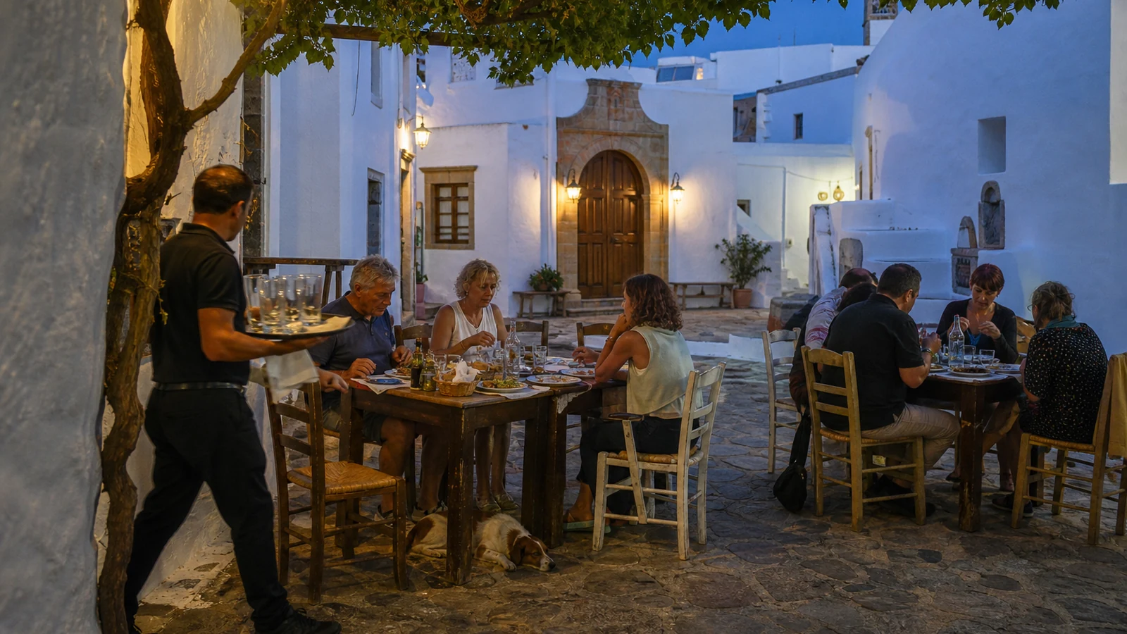 Mixed-age diners sharing an early September evening meal in a Chora square on Patmos