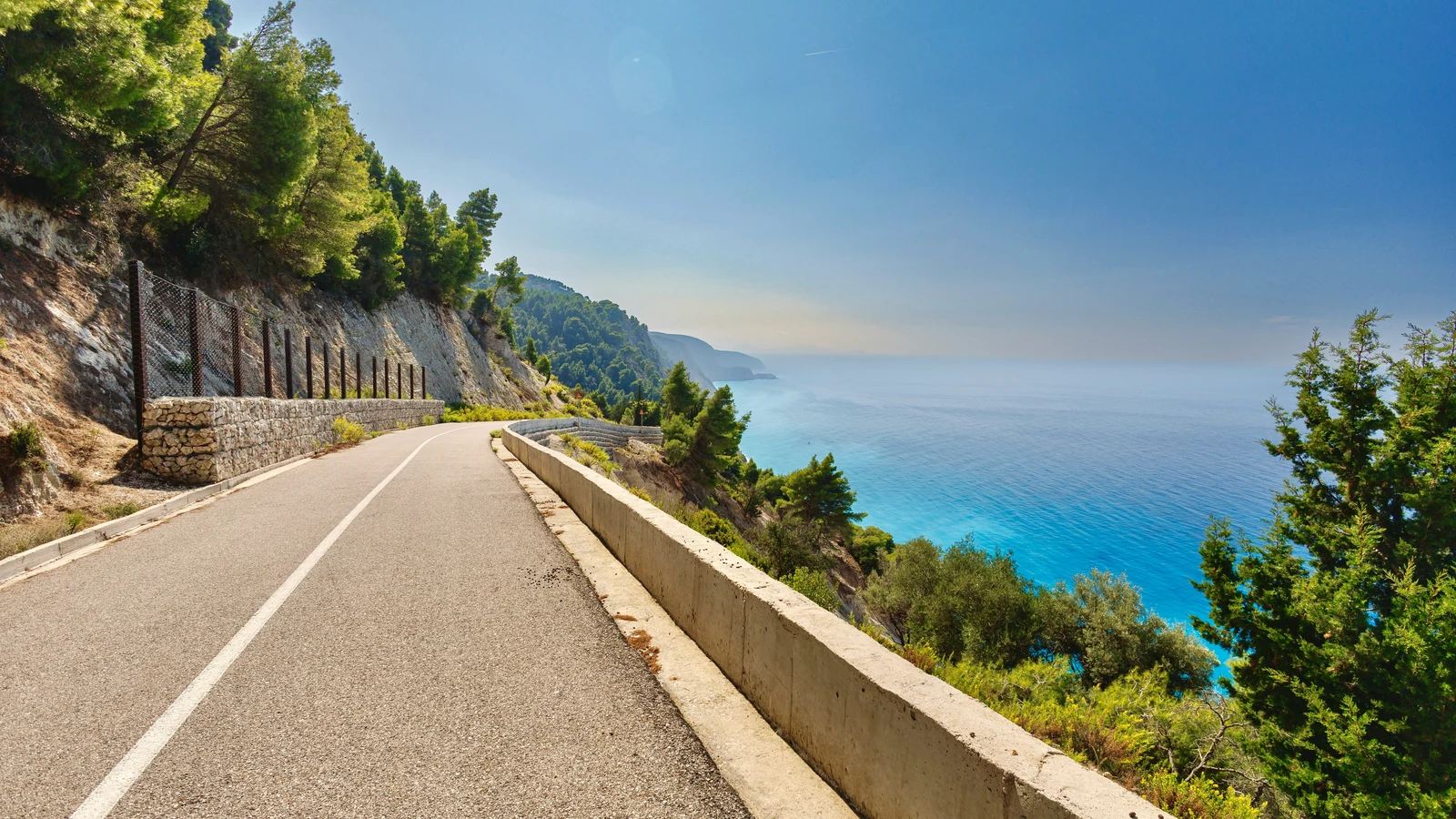 A winding road above Lefkada's steep green west coast and blue Ionian Sea