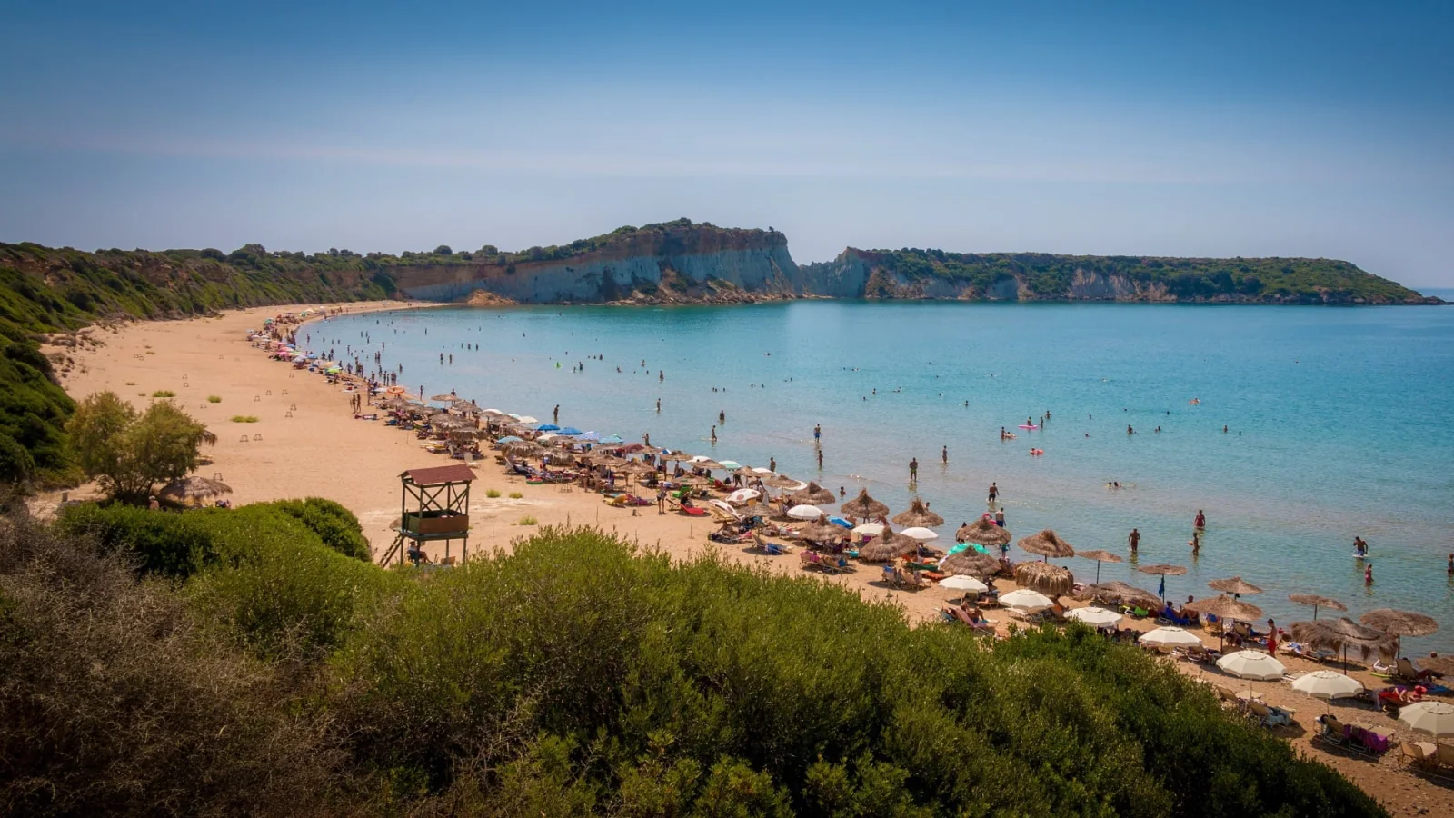 Gerakas beach in Vasilikos, Zakynthos, with a curving sandy shore and pale cliffs beyond.