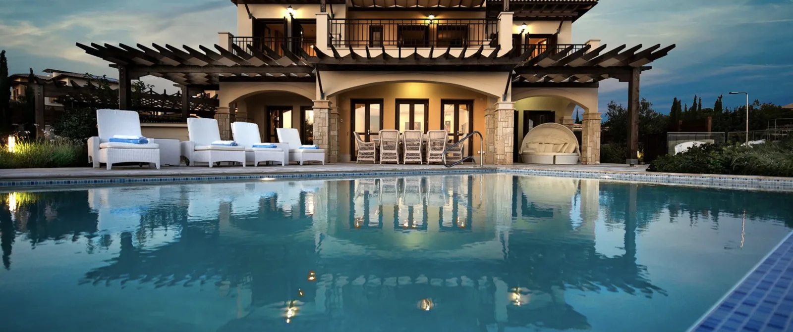 Lit poolside terrace and lounge seating at an Aphrodite Hills villa after dark
