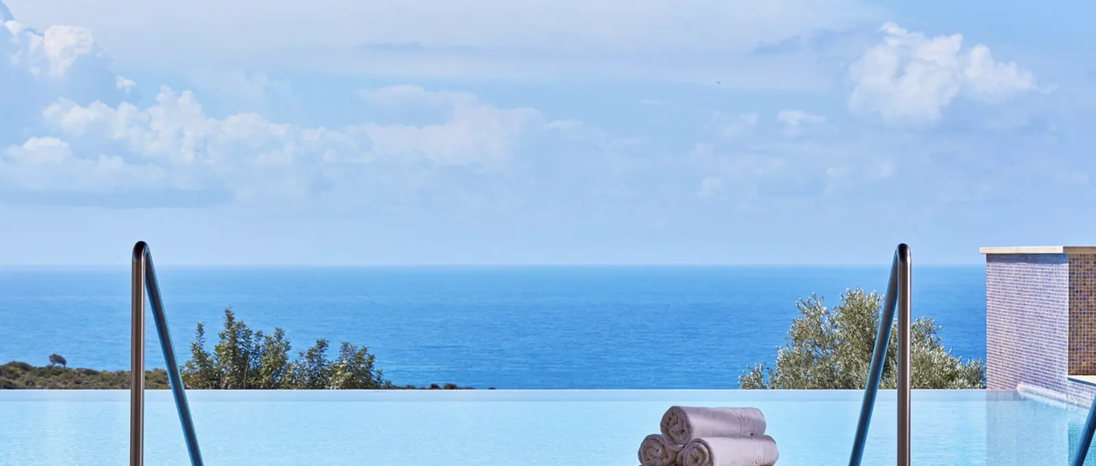 Folded towels on a sunlounger with the Mediterranean beyond