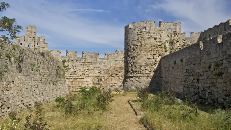 Medieval stone walls and a tower beside the dry moat in Rhodes Old Town