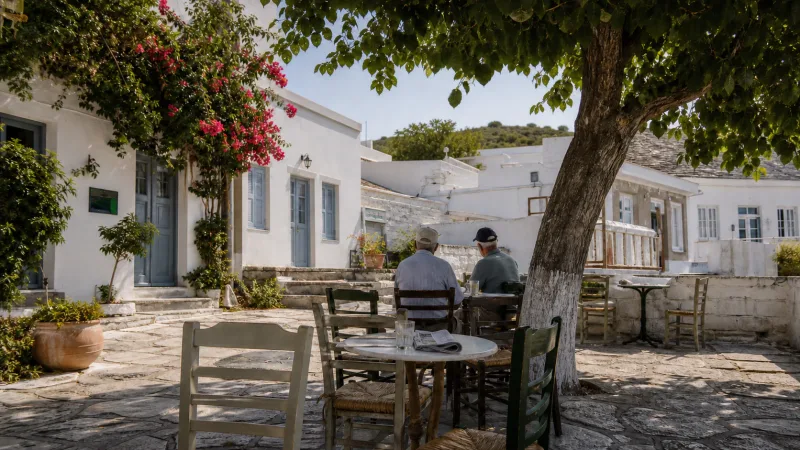 Two residents sitting at a shaded kafeneio in Lefkes village, Paros